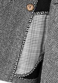 Grijze stof met een houndstooth-patroon en een houten knoop, voorzien van een zak met zwarte randen en een witte geruite voering.