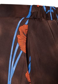 Bruine stof met een gladde textuur, voorzien van heldere oranje bloemenpatronen en blauwe lijnen. Elastische tailleband met plooien voor extra detail.