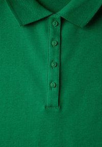 Grön bomullspolo med en texturerad yta, som har en krage och fem matchande gröna knappar på framsidan.