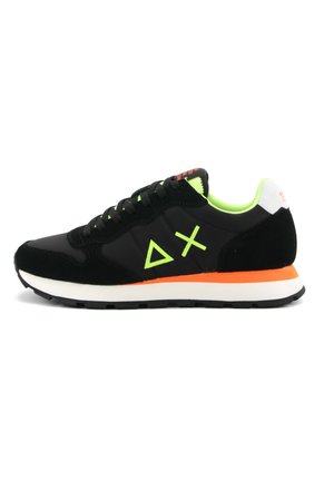 Scarpa sportiva nera realizzata in materiali scamosciati e mesh. Presenta dettagli verdi, una suola arancione e un logo geometrico sul lato.