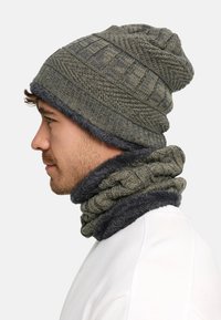 Knit beanie and matching infinity scarf in olive green with textured patterns and a soft gray trim. Both items are warm and cozy.
