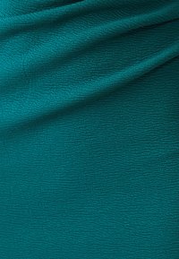 Wielokolorowa tkanina w odcieniu teal z poziomym wzorem marszczenia, o miękkim, lekkim materiale idealnym do zastosowań odzieżowych lub tapicerskich.