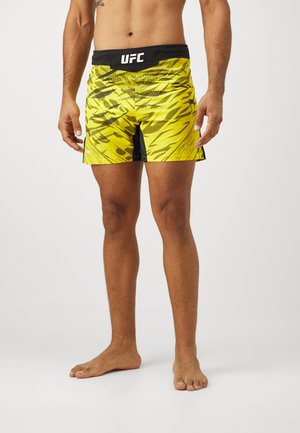 UFC-Herren Shorts in leuchtendem Gelb mit schwarzen Akzenten, ausgestattet mit einem dynamischen Muster und einem elastischen Bund, der mit "UFC" beschriftet ist.