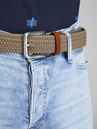 Spleciony beżowy pasek z metalową klamrą w kolorze srebrnym i brązowym skórzanym akcentem, noszony na jasnoniebieskich dżinsach z fakturowanym wzorem.