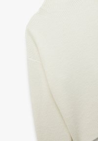 Geribbelde coltrui in off-white, met een textuurpatroon, een ontspannen pasvorm en subtiel gedefinieerde naden bij de schouders.