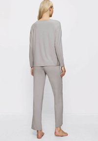 Szary zestaw odzieży domowej składający się z długiego rękawa i dopasowanych spodni. Miękka, lekka tkanina z luźnym krojem i prostymi nogawkami.