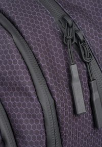 Zaino in tessuto con motivo esagonale viola, dotato di cerniere e tiranti neri, con accenti testurizzati e un design elegante.
