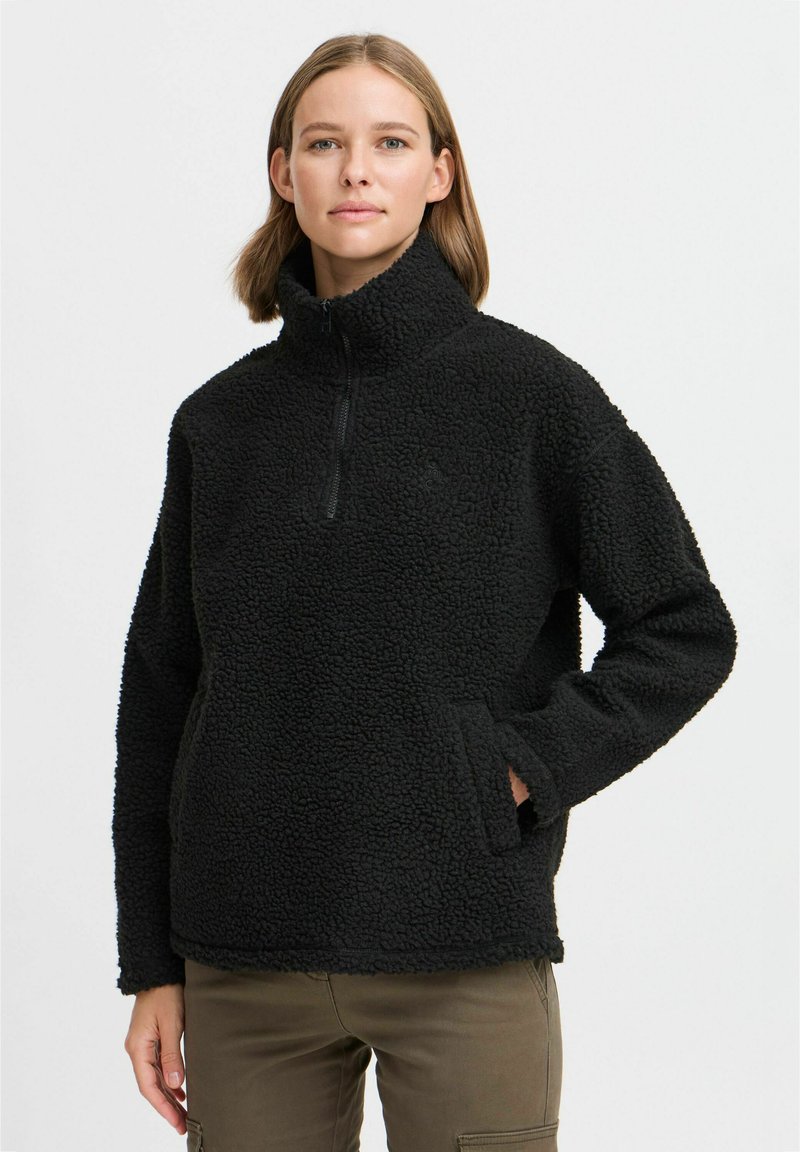 Black fleece pullover with a high collar, half-zip closure, and side pockets. Textured, soft fabric with a relaxed fit.