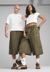 Vita kortärmade t-shirts, olivgröna cargoshorts och bruna sneakers med vita accenter. Lätt tyg, elastisk midja och sidfickor.