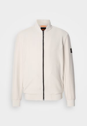 Benvit zip-up fleecejacka med ribbade cuffs och nederkant, ståkrage och svart logotypmärke på vänster ärm.