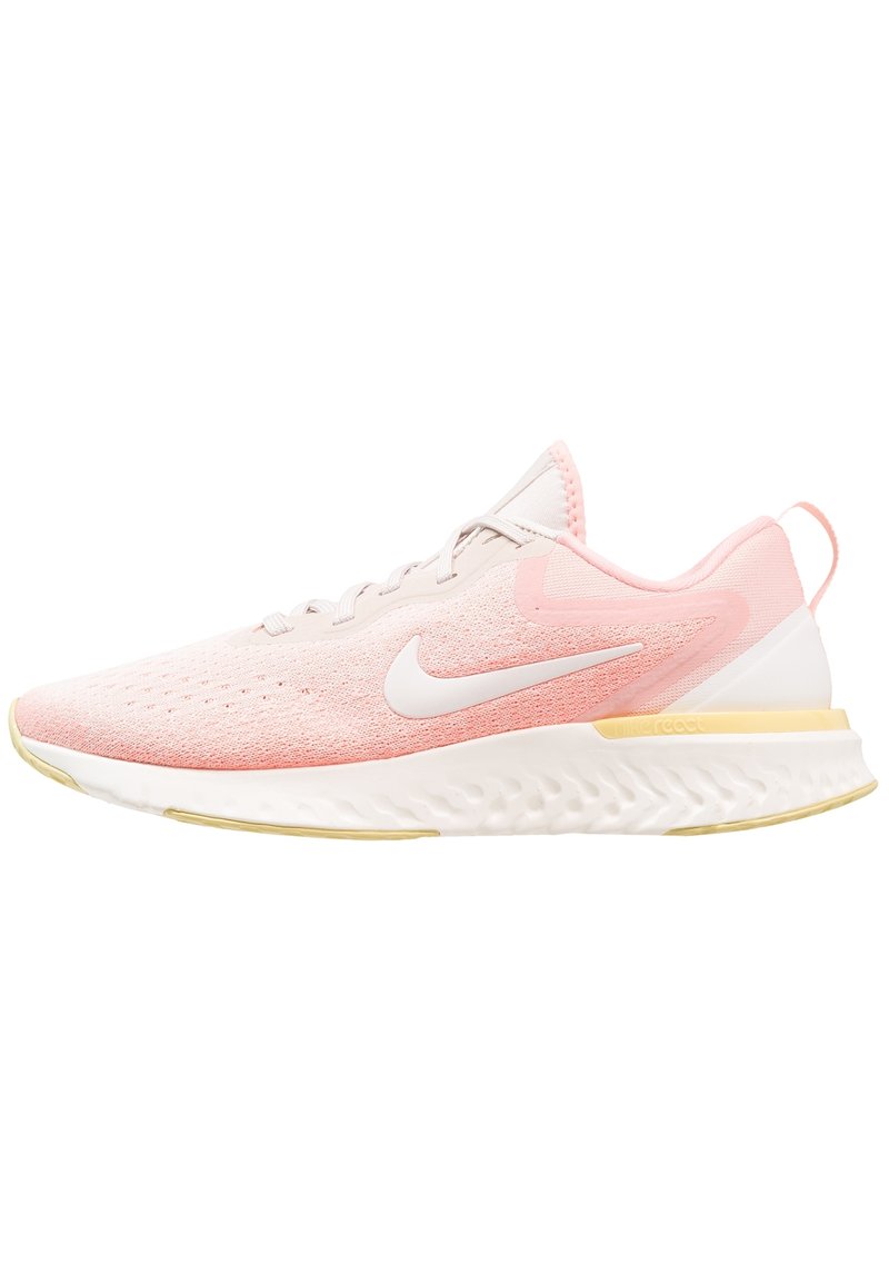 Zapatilla de running Nike de color rosa claro con logo swoosh blanco, suela blanca con acentos amarillos y parte superior de malla transpirable.