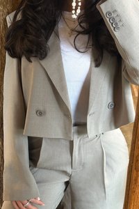 Light gray tailored cropped blazer with double buttons and structured shoulders, paired with matching high-waisted trousers. Smooth fabric texture.