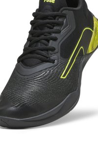 Chaussure de sport noire avec avant texturé, lacets noirs et accents jaune néon sur le côté et le talon.
