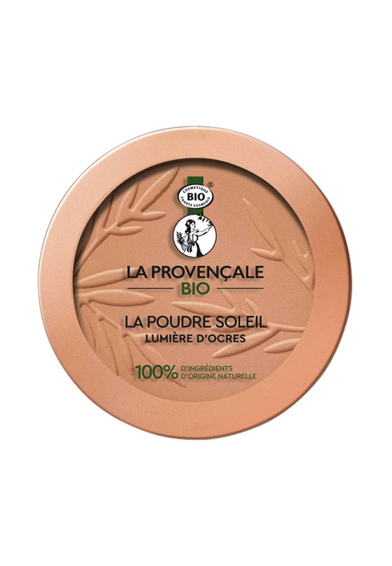 Compact rond en or rose avec un design de feuille texturé, comportant le nom du produit en noir et vert, ainsi qu'un texte indiquant des ingrédients naturels.