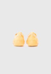 Sneakers galbene din plasă, cu o talpă din cauciuc texturată, design minimalist și bucle la spate pentru a fi ușor de încălțat.
