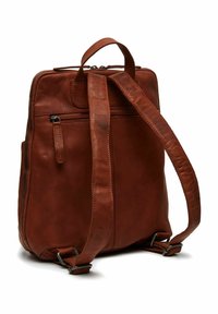 Mochila de cuero marrón con una correa ajustable, asa superior y bolsillo con cremallera en la parte delantera. Textura suave y diseño minimalista.