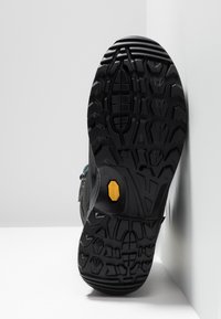 Zwarte rubberen laars zool met diepe loopprofielen. Bevat een gele Vibram-logo en gestructureerde secties voor grip. Voldoende hellend tegen een lichte achtergrond.