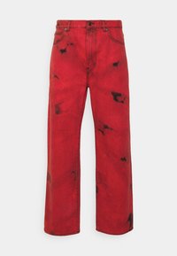 Jeans in denim rosso con vestibilità rilassata. Presentano macchie scure e irregolari e il classico stile a cinque tasche. Tessuto resistente con una superficie liscia.