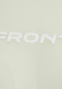 Close-up of light green textured fabric with the white letters "FRONT" printed across the surface.