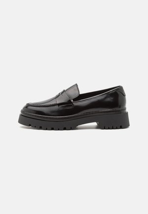 Black patent leather loafers with a chunky, ridged sole and a stitched design detail on the upper panel. Smooth finish throughout.
