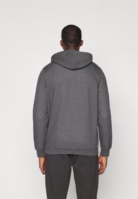 Sudadera gris hecha de tela suave, con capucha, mangas largas y puños acanalados. Diseño de espalda sin costuras, sin hardware o acentos visibles.