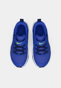 Zapatillas deportivas azules con parte superior de malla, cordones en contraste y suela blanca. Presenta un logo de Nike verde en la parte delantera. Textura suave en toda su superficie.