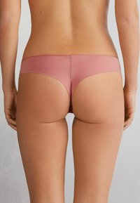 Des slips en coton stretch rose, élégants, avec une ceinture douce et un minimum de couverture à l'arrière, dotés d'une texture mate douce et d'un design sans coutures.