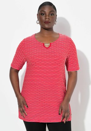 Tunic a righe rosse con maniche corte. Presenta un'apertura a chiave sul collo e un accento metallico. Tessuto morbido con una vestibilità comoda.