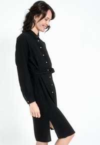 Must mustriga mustre, pikkade varrukatega, kangast vöö, külgslits ja metallnupud. Sile tekstuur, kerge materjal, kohandatud disain.