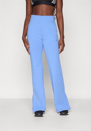 Pantaloni largi de culoare albastru deschis, confecționați dintr-un material moale, au un talie înaltă și un branding discret pe partea stângă. Textură netedă și croi lejer.