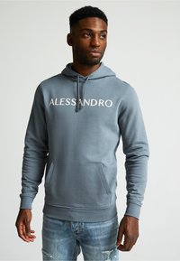 Sudadera gris con "ALESSANDRO" impreso en blanco en el pecho, con un bolsillo frontal, capucha ajustable con cordón y puños acanalados.