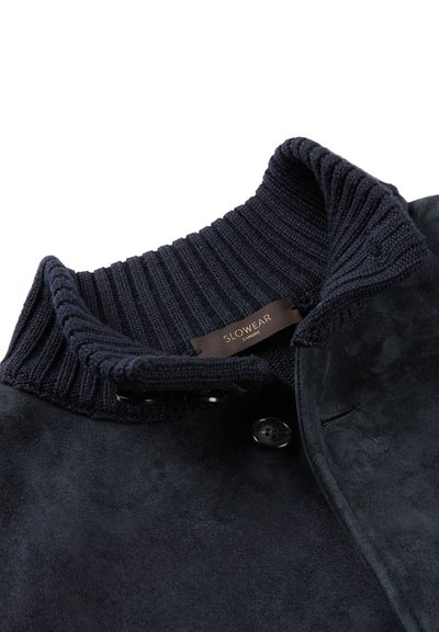 Granatowa zamszowa kurtka z prążkowanym kołnierzem, zapięciem na guziki i miękką fakturą, z metką "SLOWEAR ZANONI".