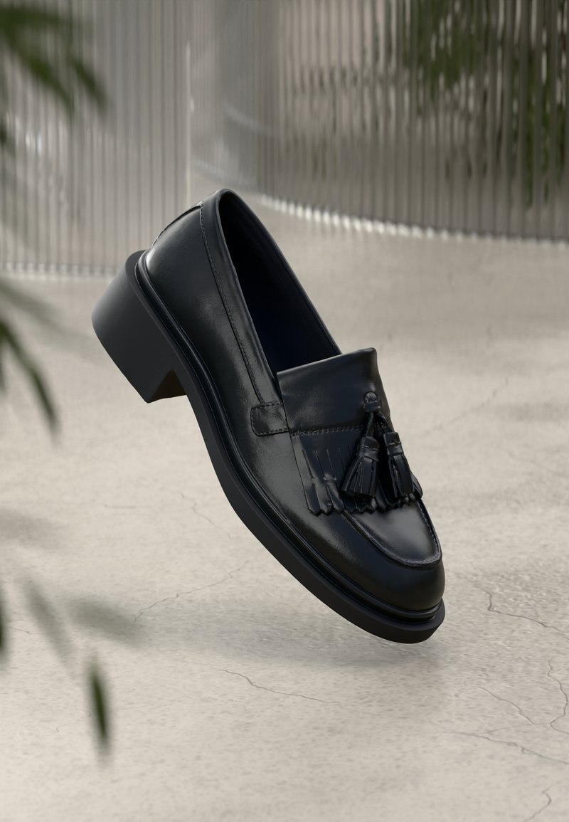 Mustat nahkakengät, joissa on tupsuakkentit, pyöreä kärki ja matala lohko korko. Sujuva pinta, jossa on selvät ompeluyksityiskohdat.