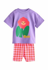Lilla kortærmet skjorte med et stort blomstermotiv i pink og grønt. Ternet røde og pink shorts med en løs pasform fuldender outfittet.