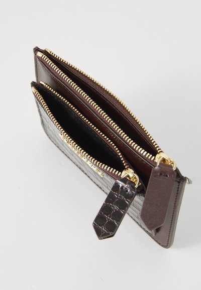 Brown leather wallet with a crocodile texture, featuring two zippered compartments and gold hardware. Includes decorative tags on zippers.