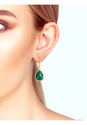 Orecchini a goccia verde sfaccettati con hardware dorato, appesi a un anello sottile, indossati in un orecchio forato su uno sfondo chiaro.