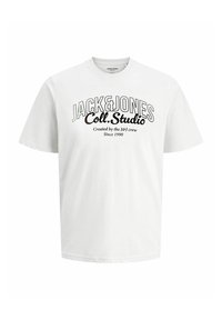 Camiseta blanca de manga corta con el texto "JACK&JONES Coll.Studio Creado por el equipo de J&J Desde 1990" impreso en letras negras y gruesas en el frente.