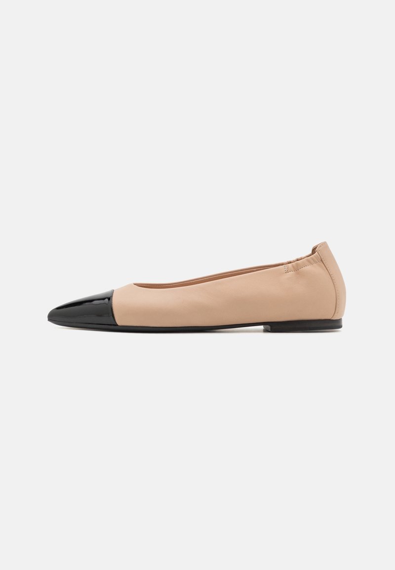 Chaussure plate beige avec un bout pointu noir brillant, un talon élastiqué et une semelle noire basse, présentée de profil sur un fond blanc.