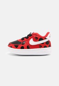 Dětské tenisky v červené a černé kůži se leopardím vzorem, bílým logem Nike, černými tkaničkami a bílou texturovanou gumovou podrážkou.