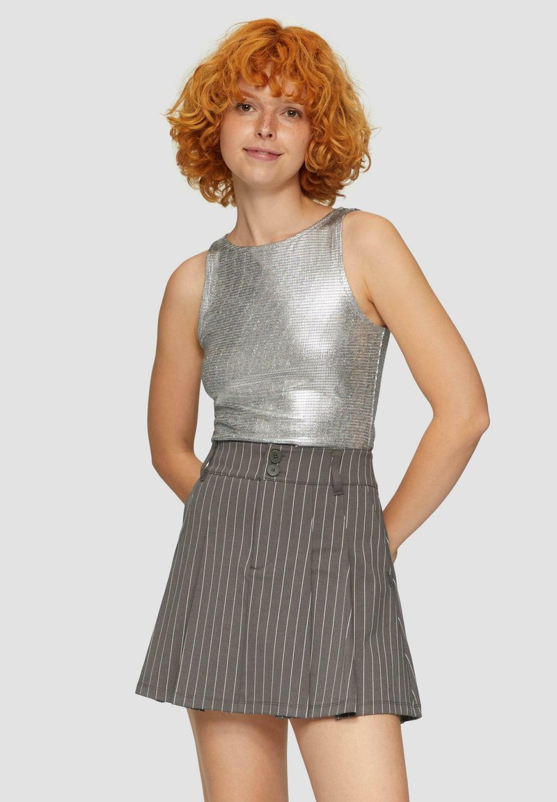 Metalen zilveren mouwloze top met een getailleerd ontwerp, gecombineerd met een grijze pantalonrok met streepjes en een knoopsluiting, afgewerkt met een uitlopende zoom.