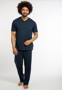 Himmelblaues Baumwoll-Loungewear-Set bestehend aus einem kurzärmeligen V-Ausschnitt-Oberteil mit einer Brusttasche und passenden lässigen, weit geschnittenen Hosen. Glatte Textur.