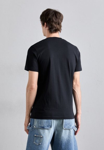 Svart kortermet T-skjorte laget av bomull, med rund hals og en jevn tekstur, brukt sammen med lyseblå denimjeans.