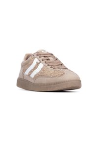 Zapatillas beige con ante texturizado y acentos esponjosos, que presentan rayas blancas, puntera redonda y cordones marrones sobre una suela de goma flexible.