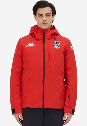 Giacca isolante rossa con zip frontale, cappuccio e logo Kappa. Presenta toppe della US Ski Team, polsini elasticizzati e tasche laterali.
