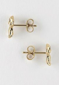 Goldfarbene Ohrstecker in Form von Teddybären mit schwarzen Augen, seitlich auf einem weißen Hintergrund dargestellt.