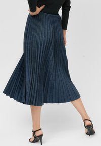 Donkerdenim plissé rok in midi-lengte, met een aansluitende tailleband en een zachte textuur. De achterkant toont duidelijke verticale plooien en een uitlopende zoom.