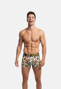 Boxers pour hommes avec une base jaune, ornés d'un imprimé léopard multicolore. Ceinture noire avec le logo "MR UKKO", coupe ajustée, texture lisse.