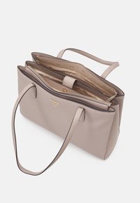 Sac à main beige en matériau synthétique texturé, avec un compartiment principal zippé et deux poignées ; détails en métal doré.