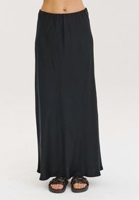 Čierna maxi sukňa vyrobená z hladkej, ľahkej tkaniny, s elastickým pásom. V kombinácii s tmavými, tkanými sandálmi.