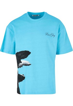 Gaiši zila kokvilnas T-krekls ar melnbaltu govs grafiku vienā pusē un tekstu "Gods un Slava" skriptu fontā.